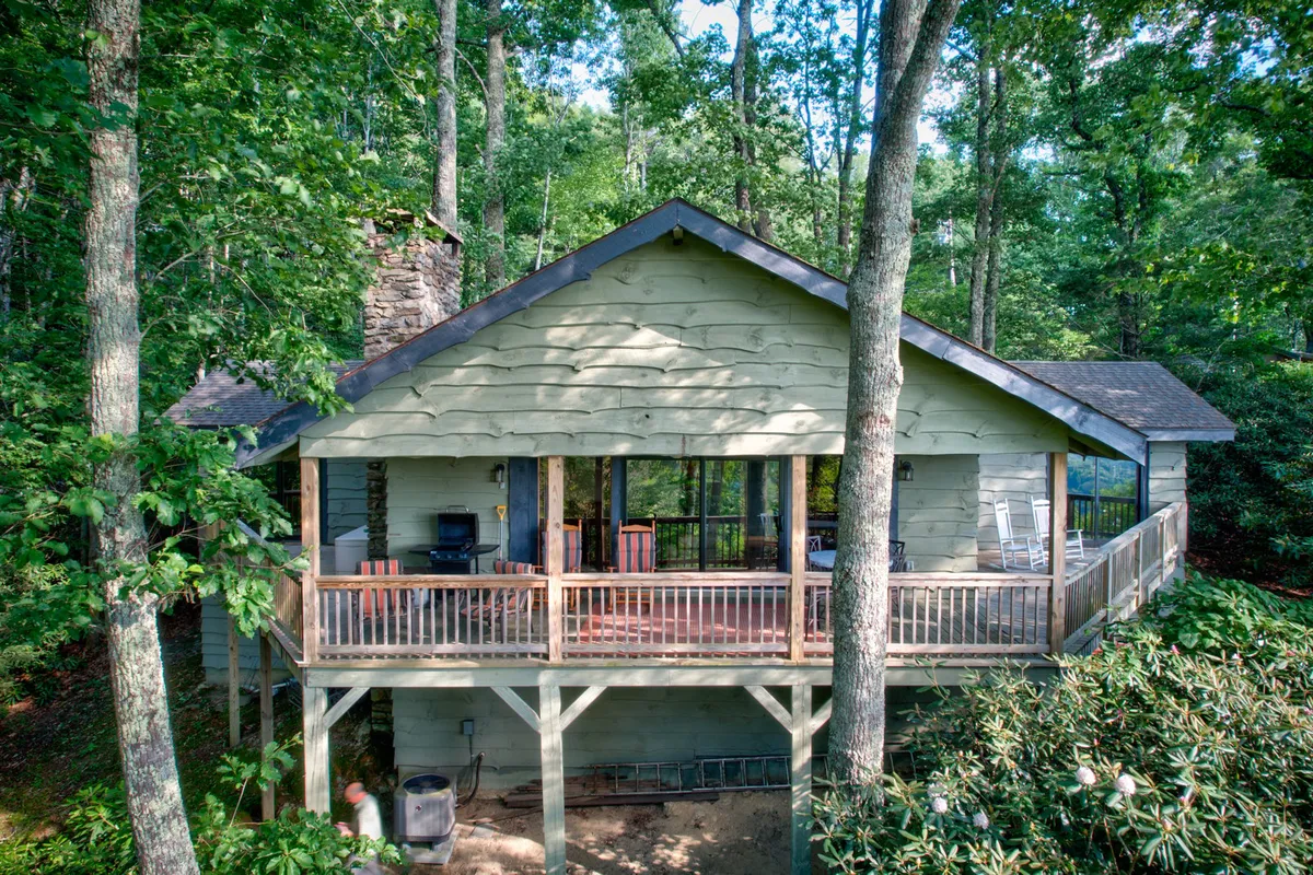 A peaceful wooden deck bordered by tall trees and featuring a stone chimney, offering a tranquil spot to enjoy the mountain surroundings. The deck provides panoramic views, making it an ideal place to relax and take in the scenery after a day of adventure.