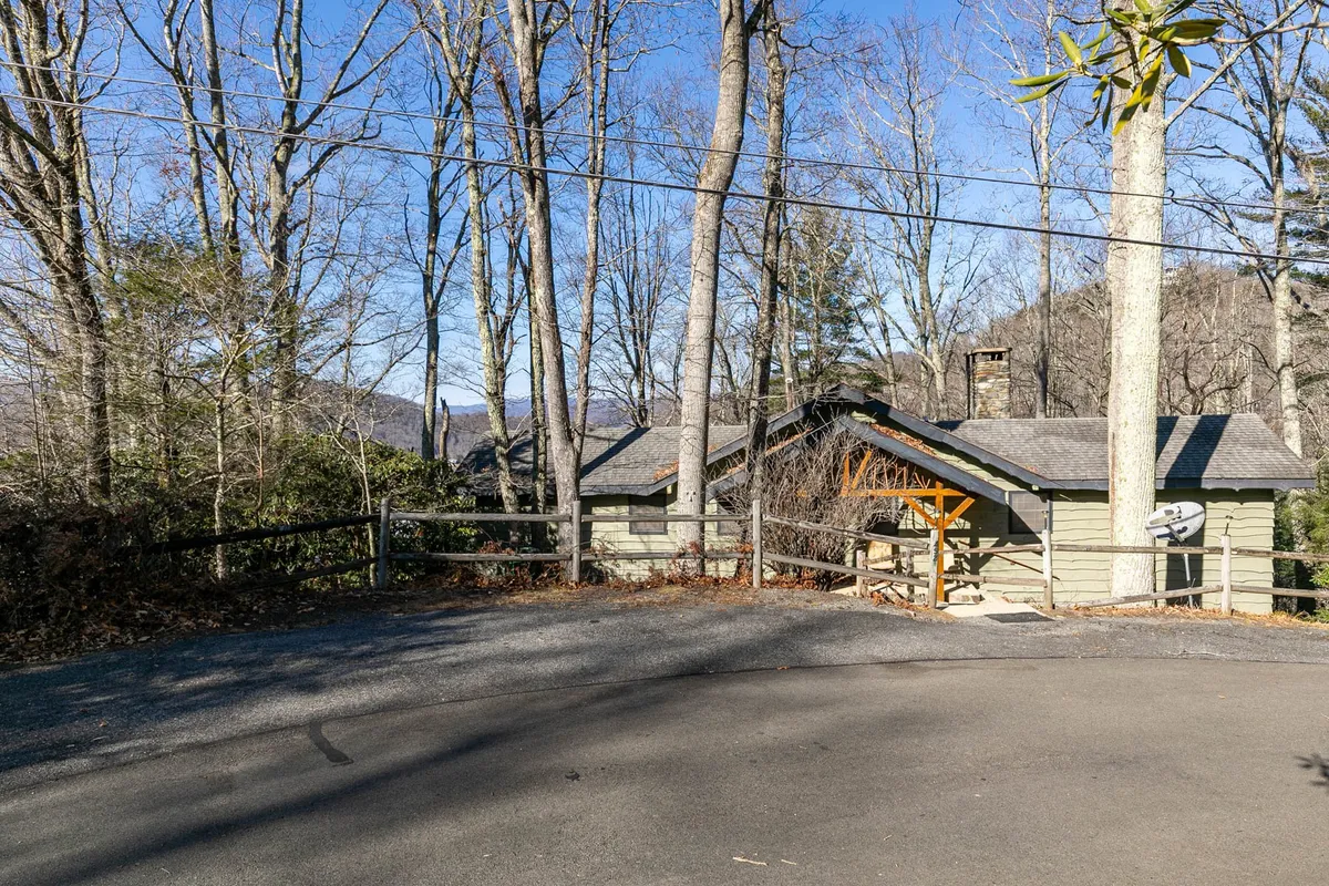 A wide exterior view of the house surrounded by mature trees and a driveway, presenting both the serenity and accessibility of the basecamp. The image captures the home’s position amidst the mountains and the sense of a peaceful retreat.