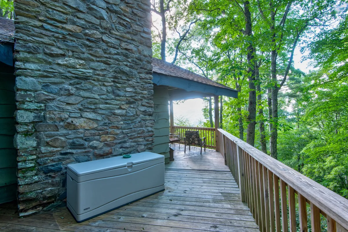 A serene wooden deck with a sturdy stone wall, surrounded by trees and featuring an inviting outdoor seating area. The deck offers sunset views and opportunities for wildlife spotting, creating an ideal spot to unwind with your pet after a day of adventure.