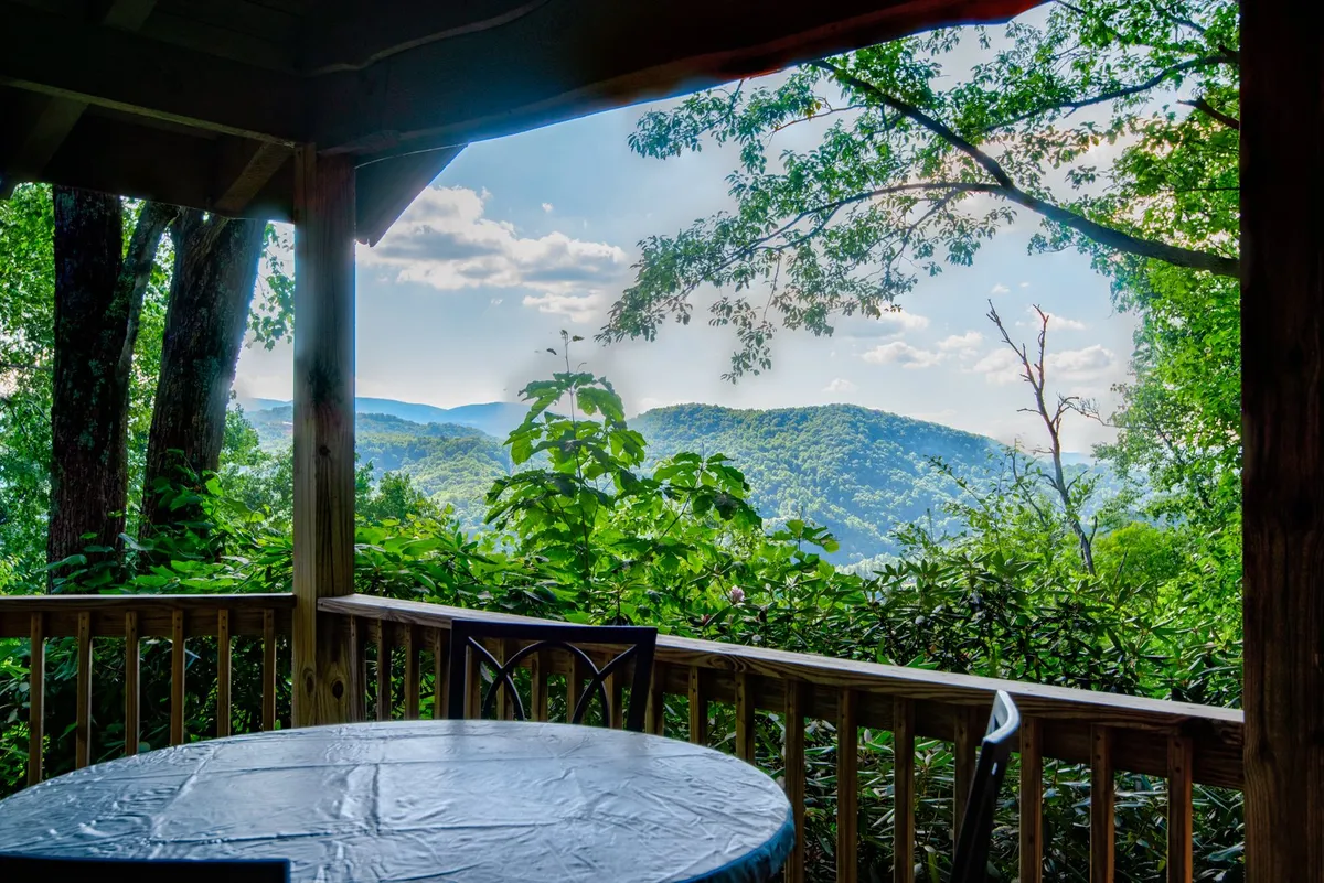 A peaceful deck scene with a table setting, wooden railing, and a clear view of the distant mountain range. The composition encourages outdoor dining or relaxation while enjoying natural scenery, and the overall ambiance is tranquil and picturesque.